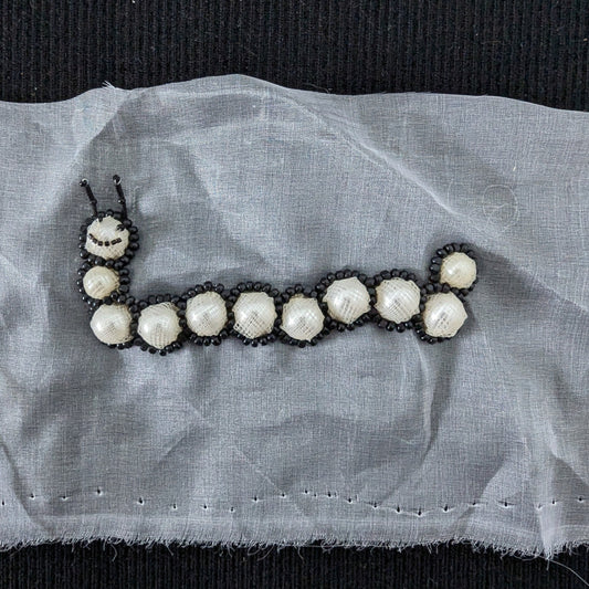 D&G 10cm pearl and black bead caterpillar patch on white fabric.