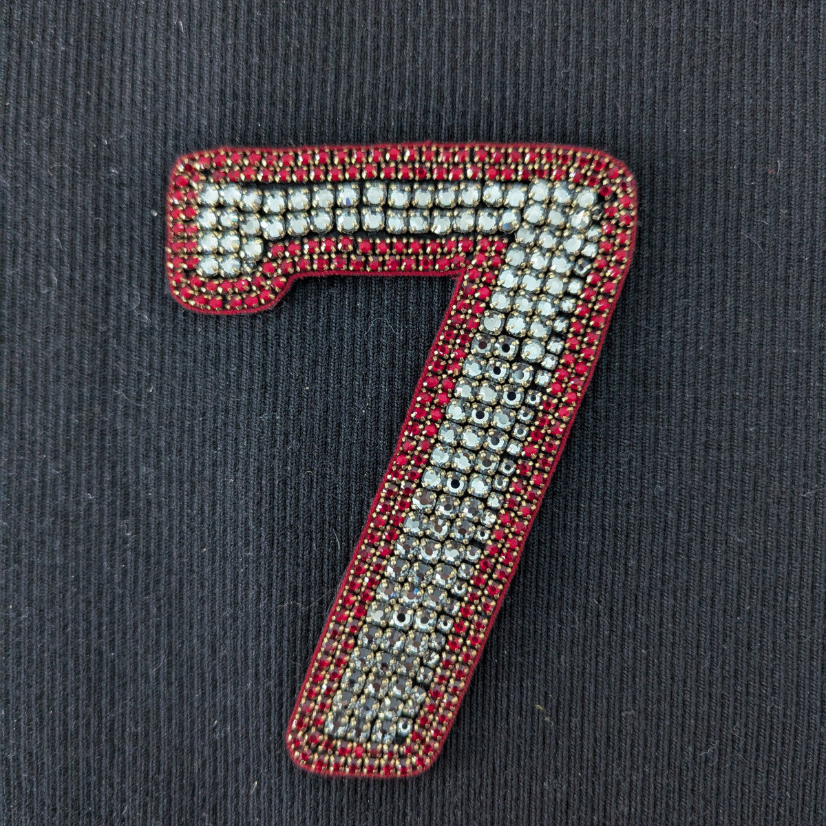 D&G number 7 patch with white and red pearl embroidery on a black background.