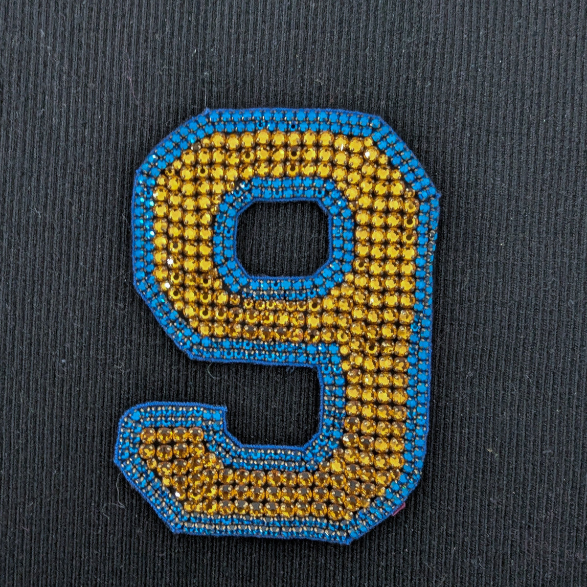 D&G patch, number 9, with gold sequins and blue beaded trim, 10 cm, on black fabric.