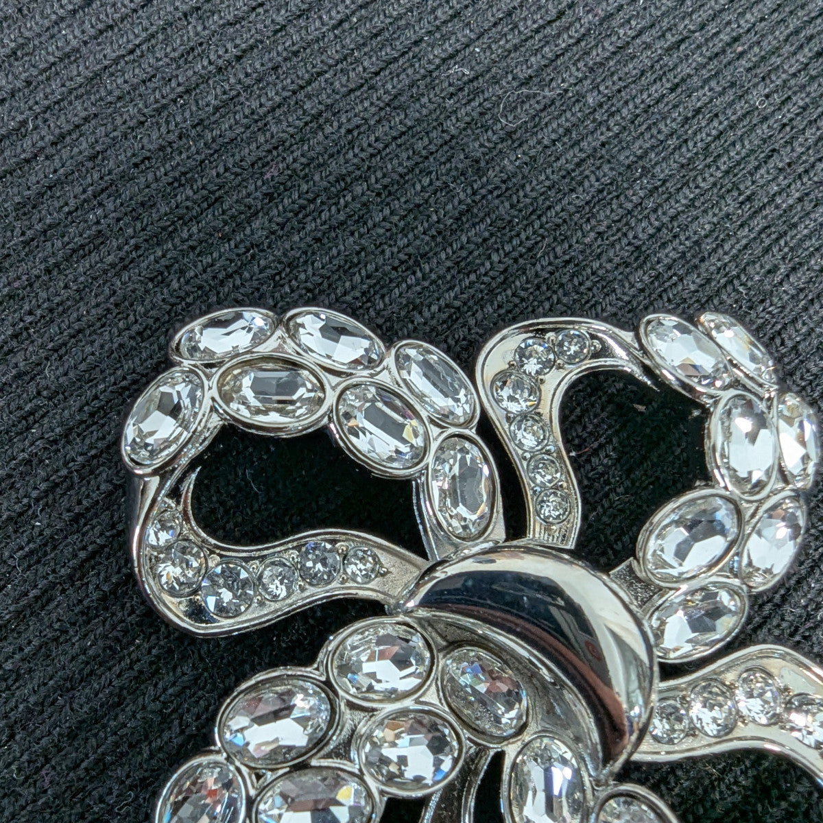 D&G silver-plated bow ornament with sparkling Swarovski stones on a black background.