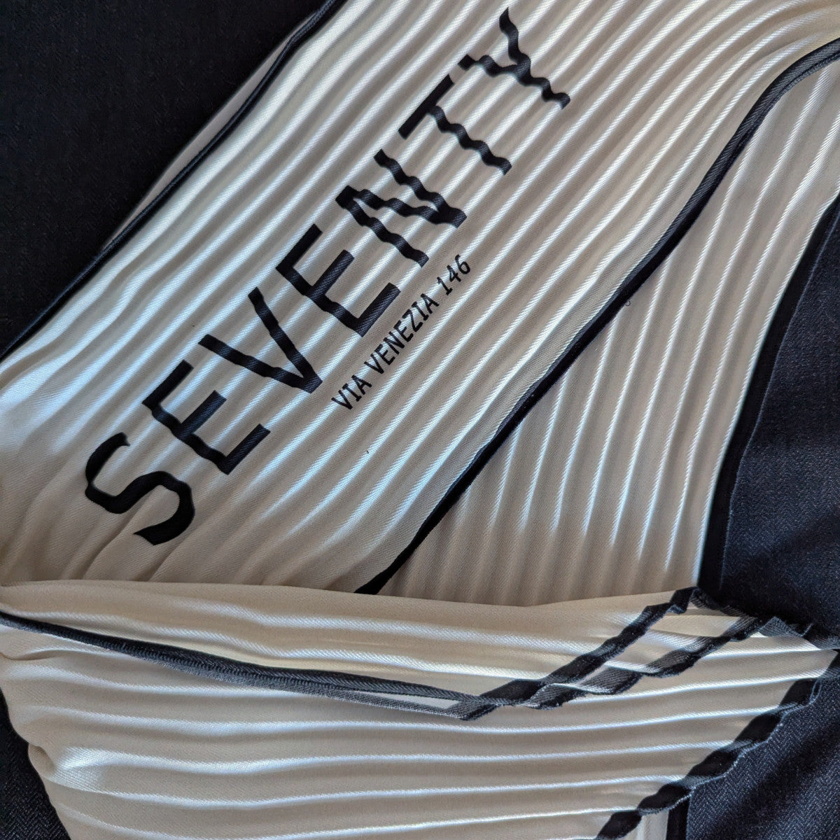 Pleated silk twilly with "SEVENTY VIA VENEZIA 146" text, off-white with black trim.