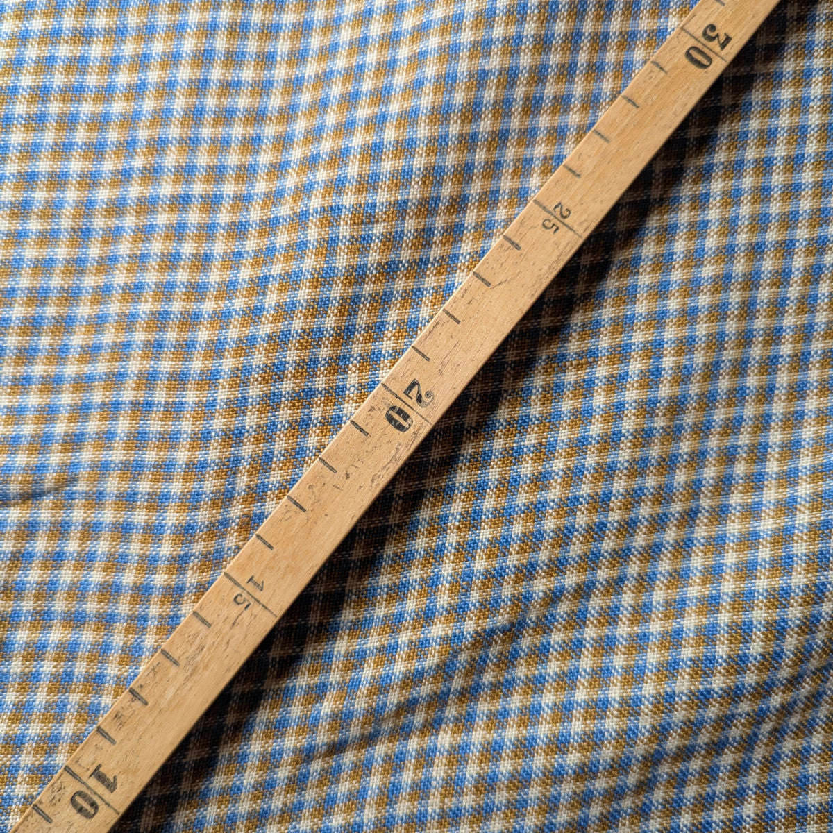 Blue and brown checked linen-cotton blend fabric with natural texture, measured by a wooden ruler.