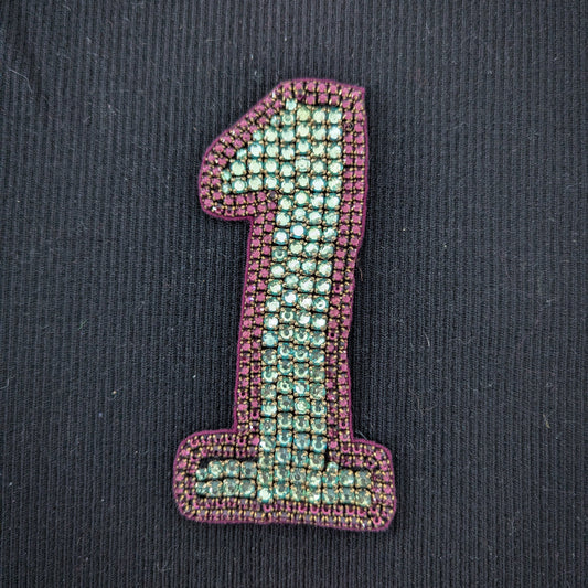 D&G "1" patch with sparkling turquoise beads and a purple embroidered border on black fabric.
