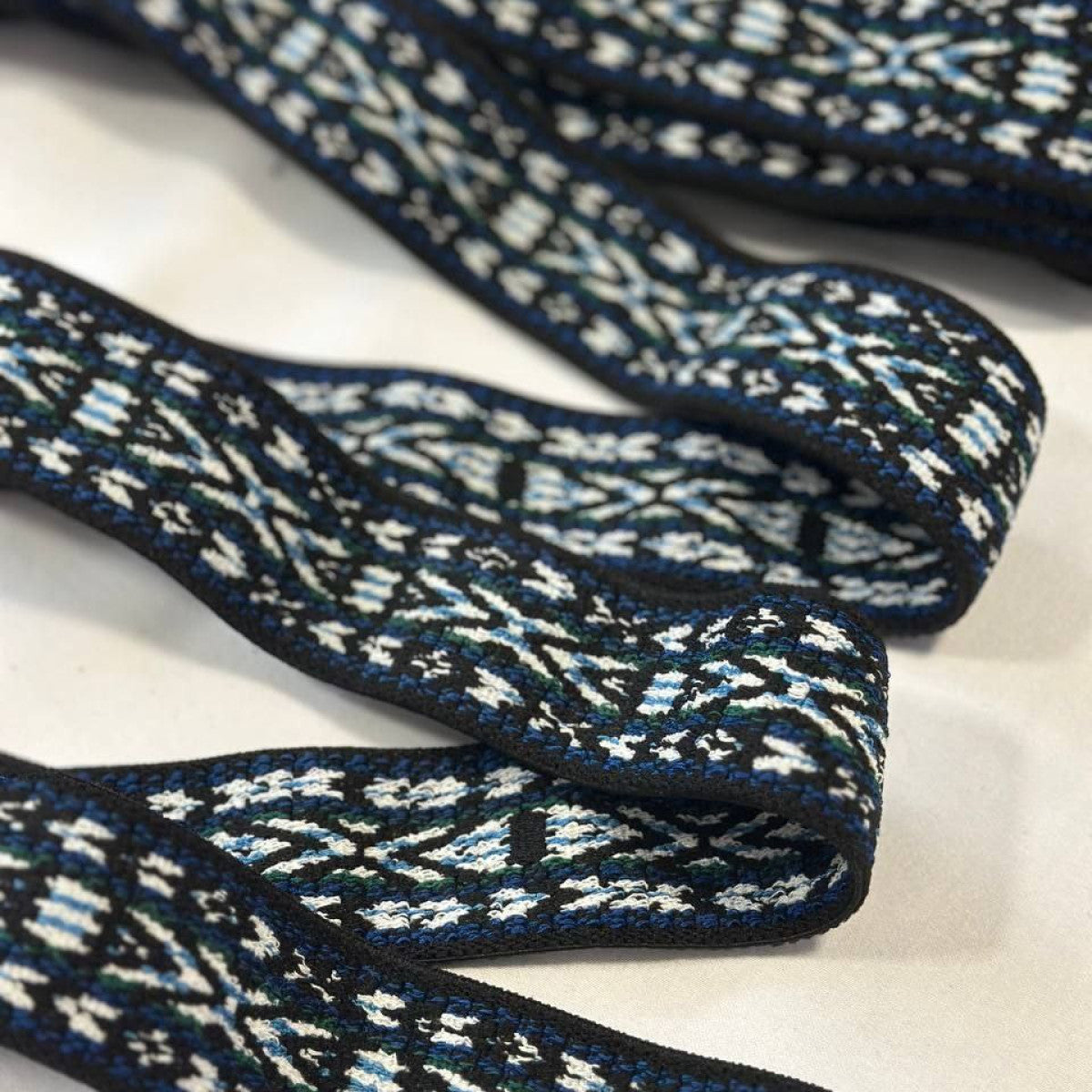 Black, blue, and white patterned woven trim with geometric design.