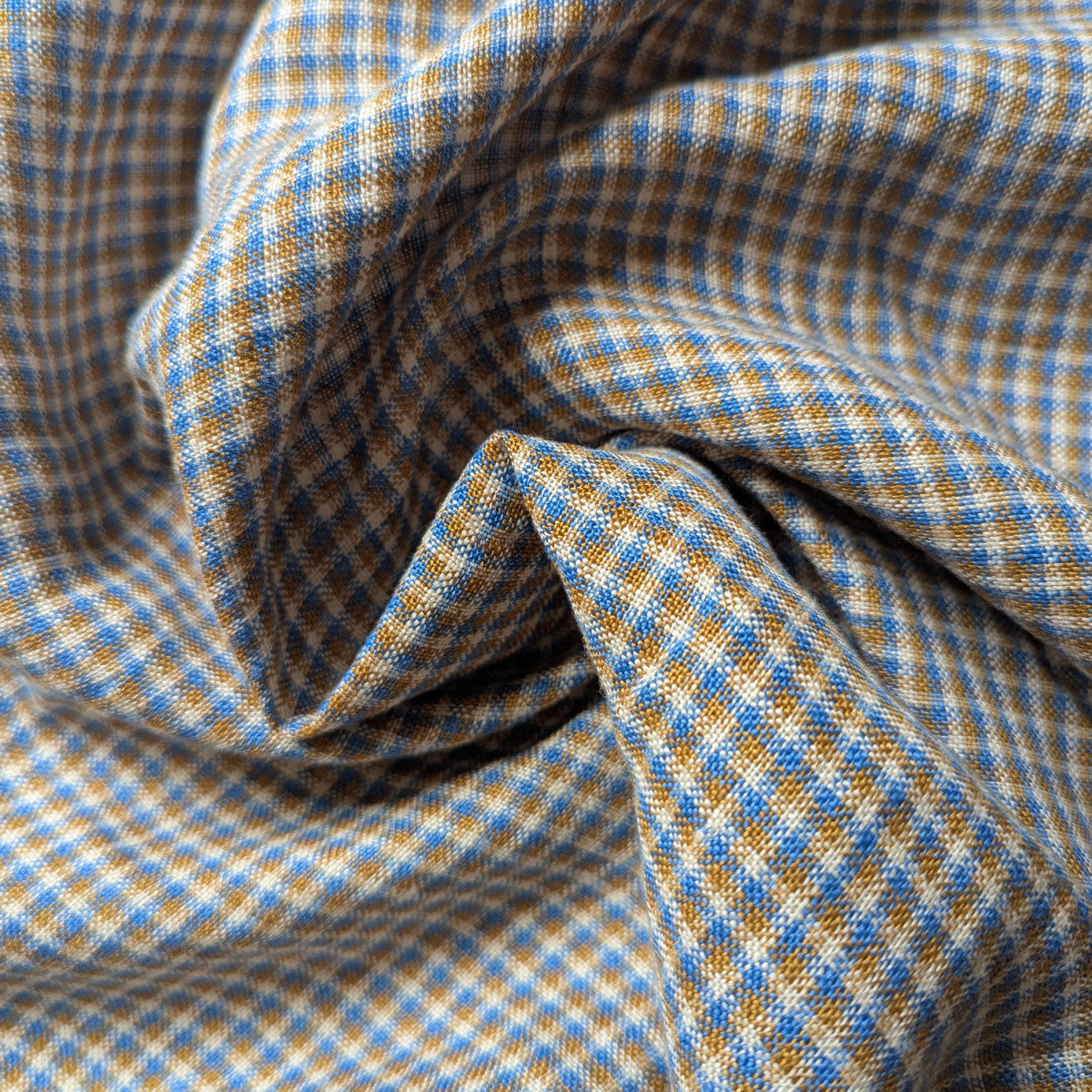 Deadstock linen-cotton blend fabric, light blue and golden brown checked pattern, natural texture.