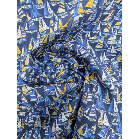 Swirled dark blue deadstock cotton poplin fabric with yellow, blue, and white sailboat print.