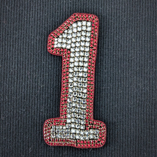 D&G number 1 patch with sparkling silver beads and a red beaded border on black fabric.