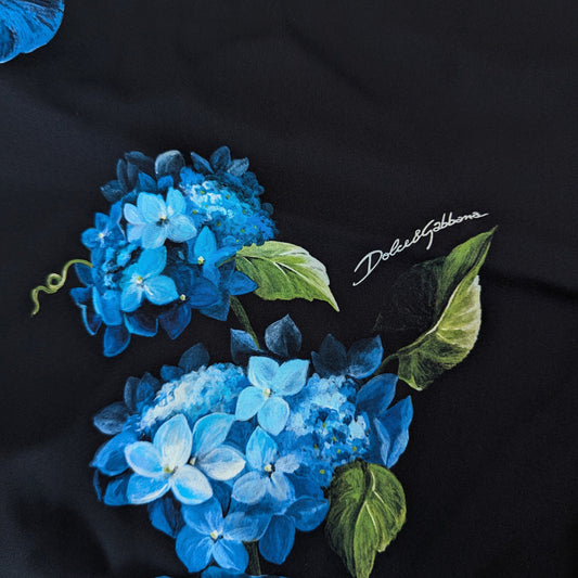 Black silk fabric with vibrant blue hydrangea floral print and "Dolce&Gabbana" logo.