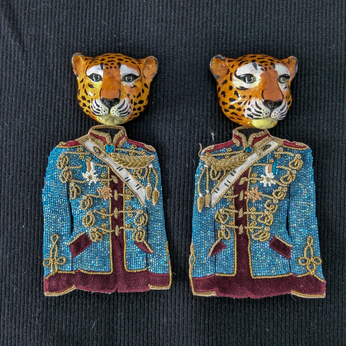 Two embroidered D&G leopard head patches with blue, gold, and maroon uniform jackets.