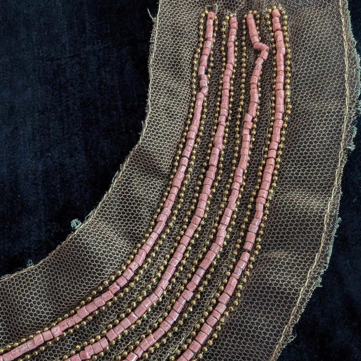 D&G pink pearl and gold beaded patch on sheer brown mesh, against a black background.