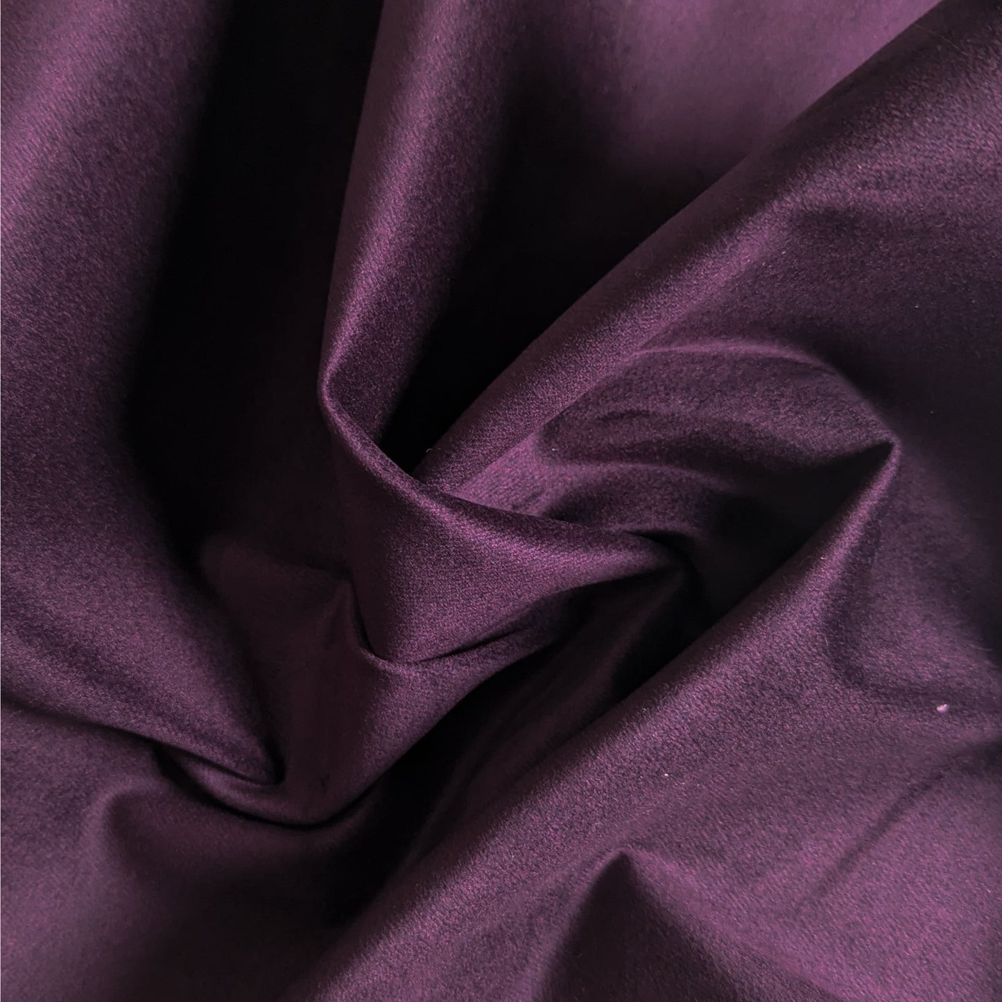 Luxurious aubergine elastic velvet denim fabric, deadstock, showcasing its soft, velvety texture and elegant drape.