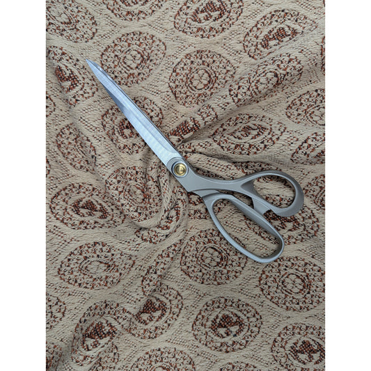 Beige cotton jacquard fabric with brown circular patterns and silver scissors.