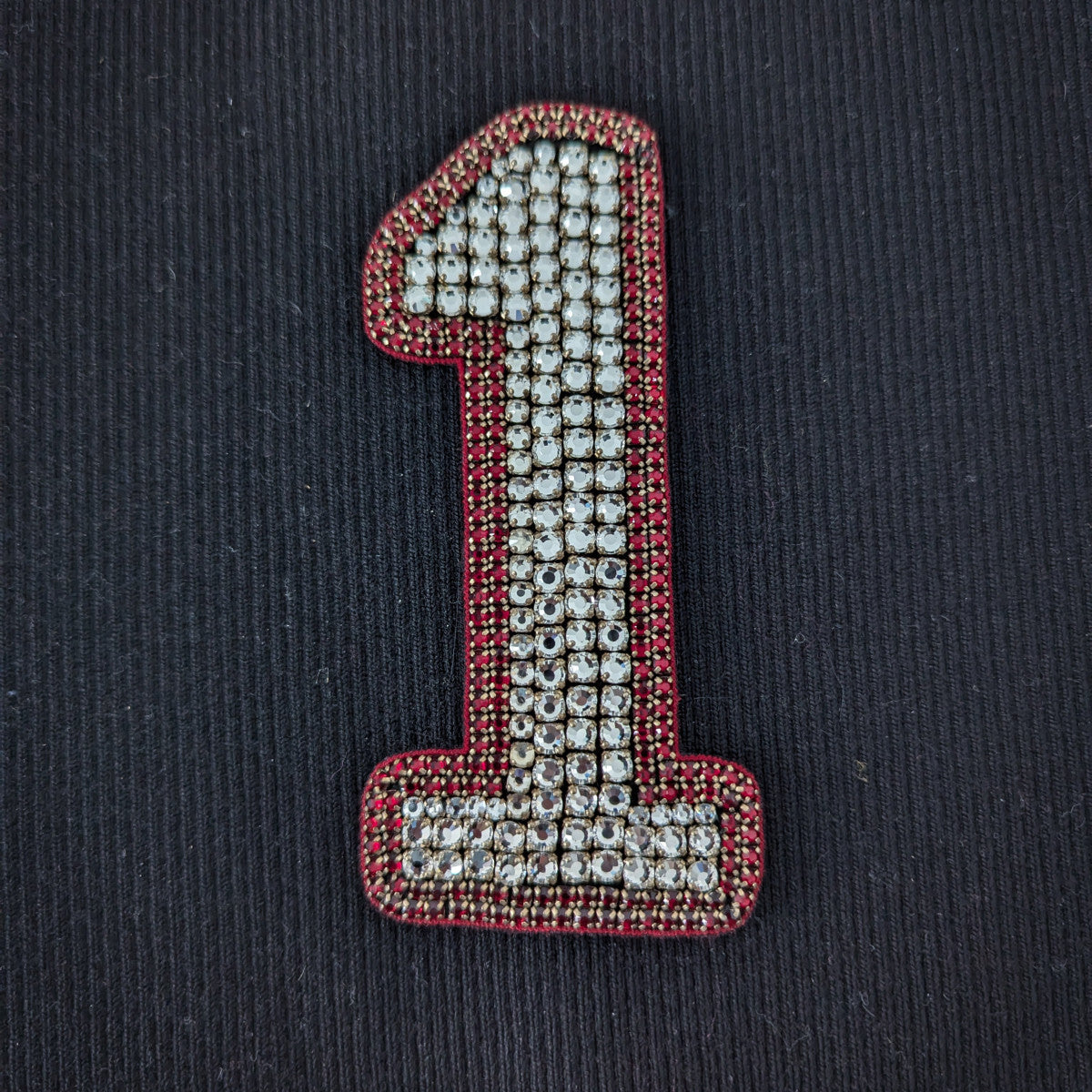 D&G number 1 patch with sparkling clear pearls and red beaded trim on a black background.