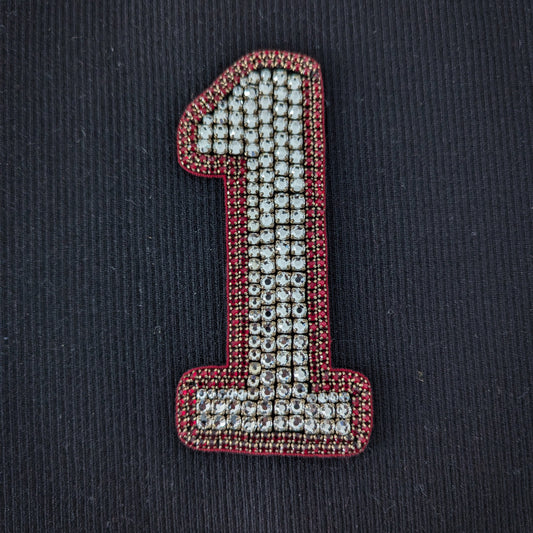 D&G number 1 patch with sparkling clear pearls and red beaded trim on a black background.