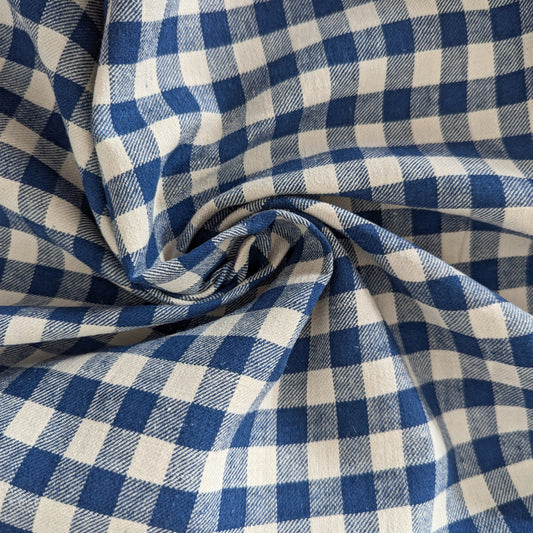 Blue and natural white gingham check cotton fabric, 145 cm wide, shown in a soft swirl.