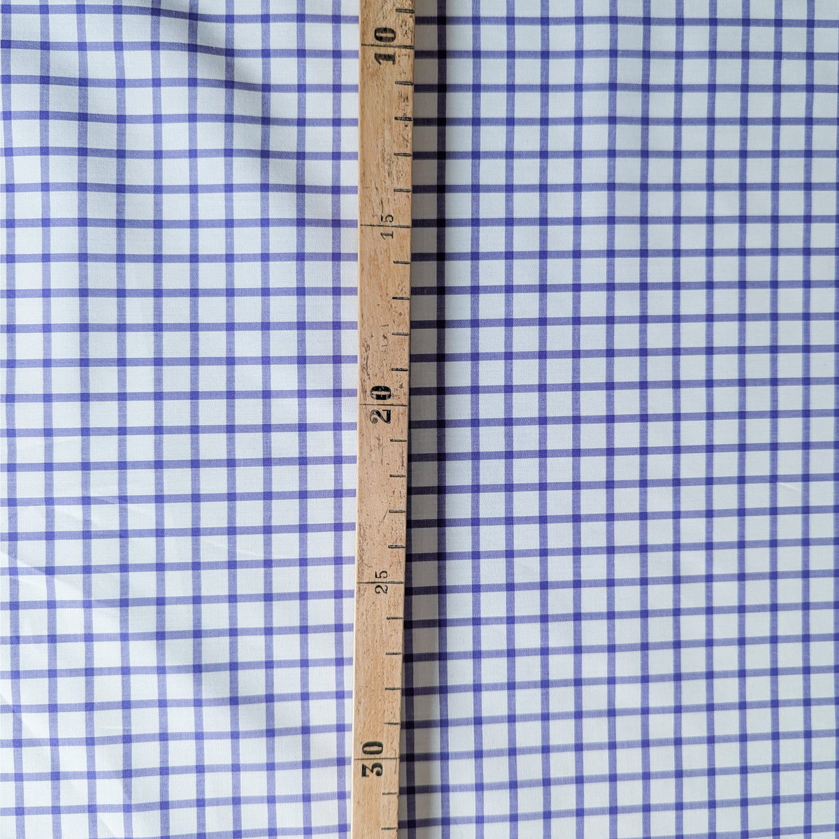 White and purple checkered E##o cotton poplin fabric with a wooden ruler.