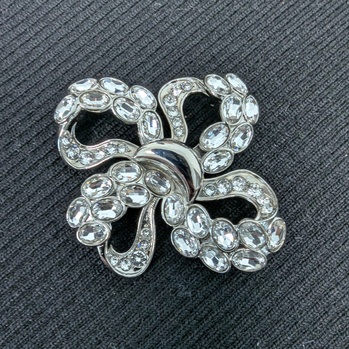 D&G silver-plated metal ornament with sparkling Swarovski stones, 4x4cm filigree bow design.