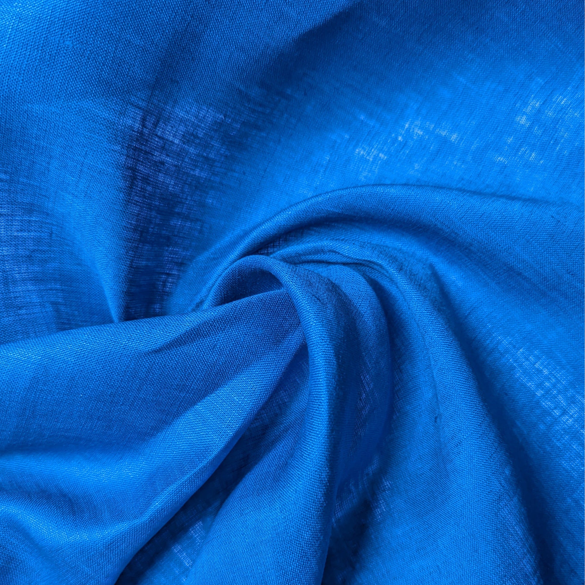 Deadstock chinose blue linen fabric, unicolor with a subtle sheen, draped in soft folds.