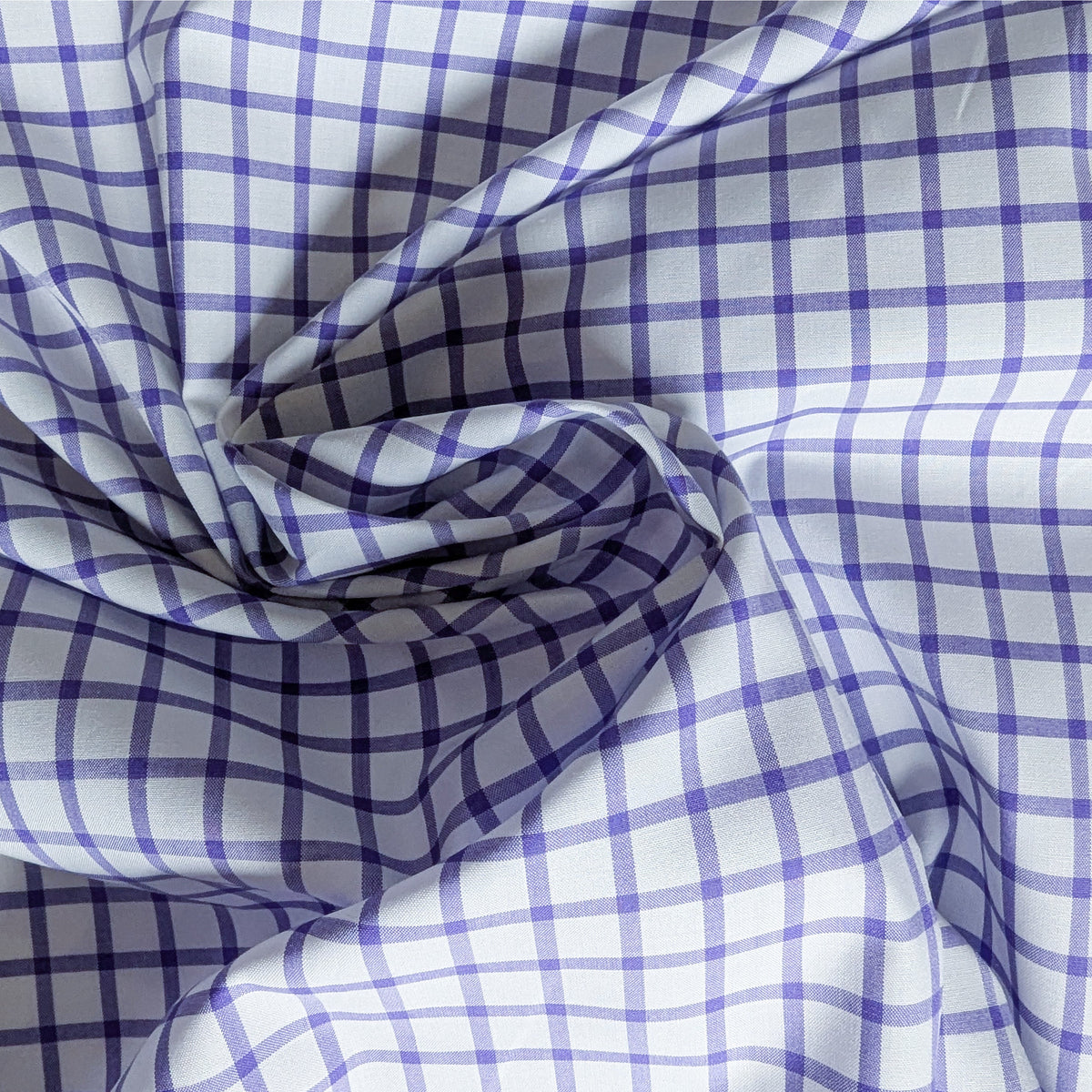 White and purple checkered Baumwollpoplin deadstock fabric, draped with a soft swirl.