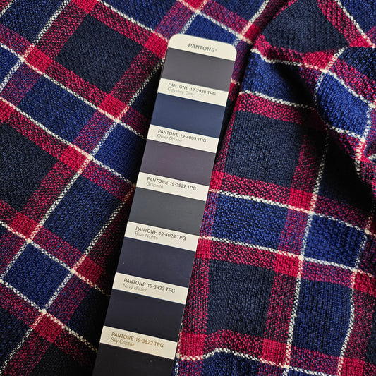Deadstock tweed cotton fabric, 140cm wide, with a blue, red, and white plaid pattern and a Pantone color swatch.