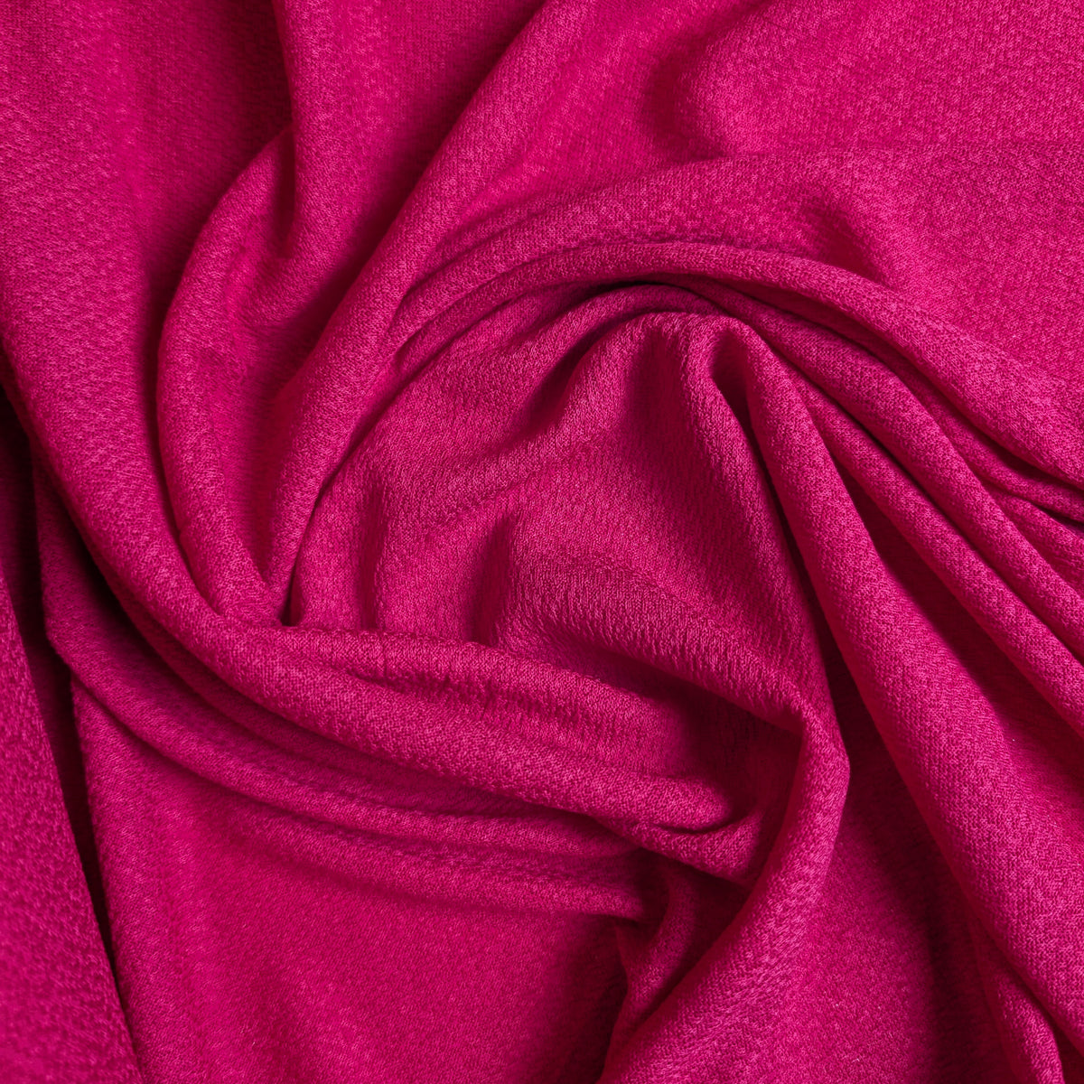 Fuchsia pink viscose crepe fabric, draped with soft folds, showing its textured surface.