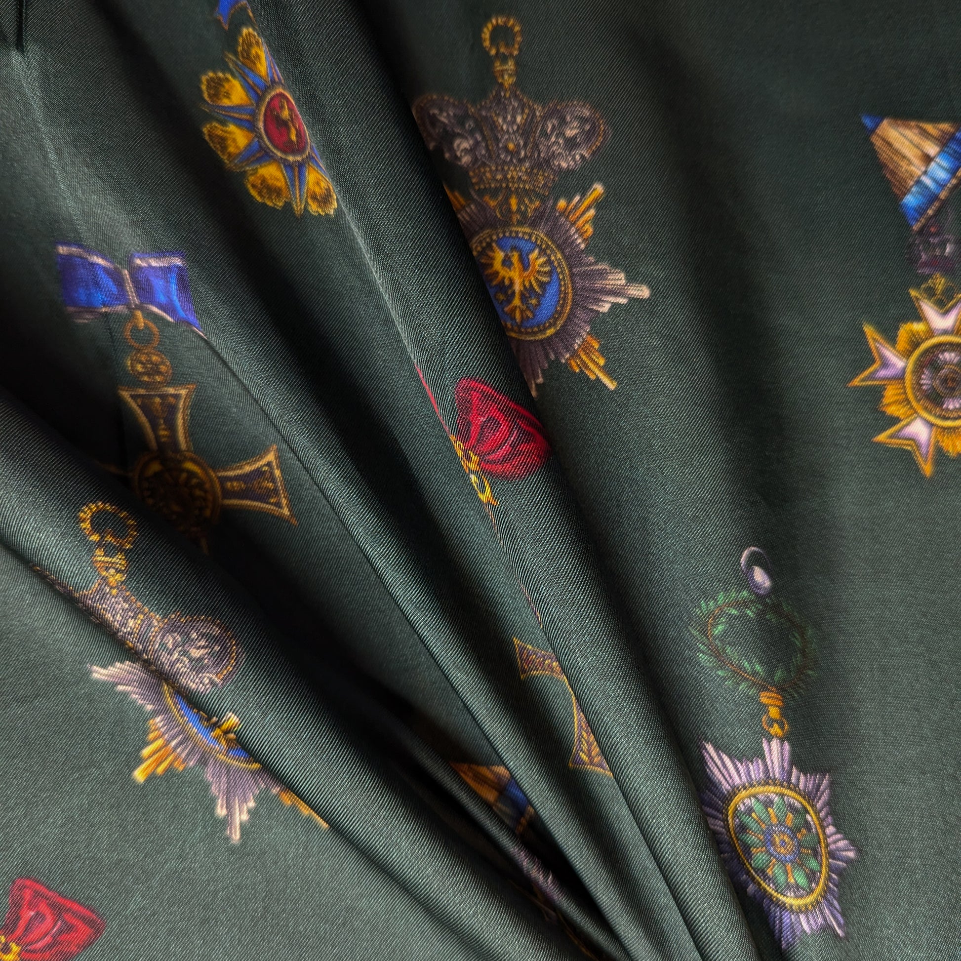 Deadstock D&G viscose twill fabric in British green with colorful military order medal print.