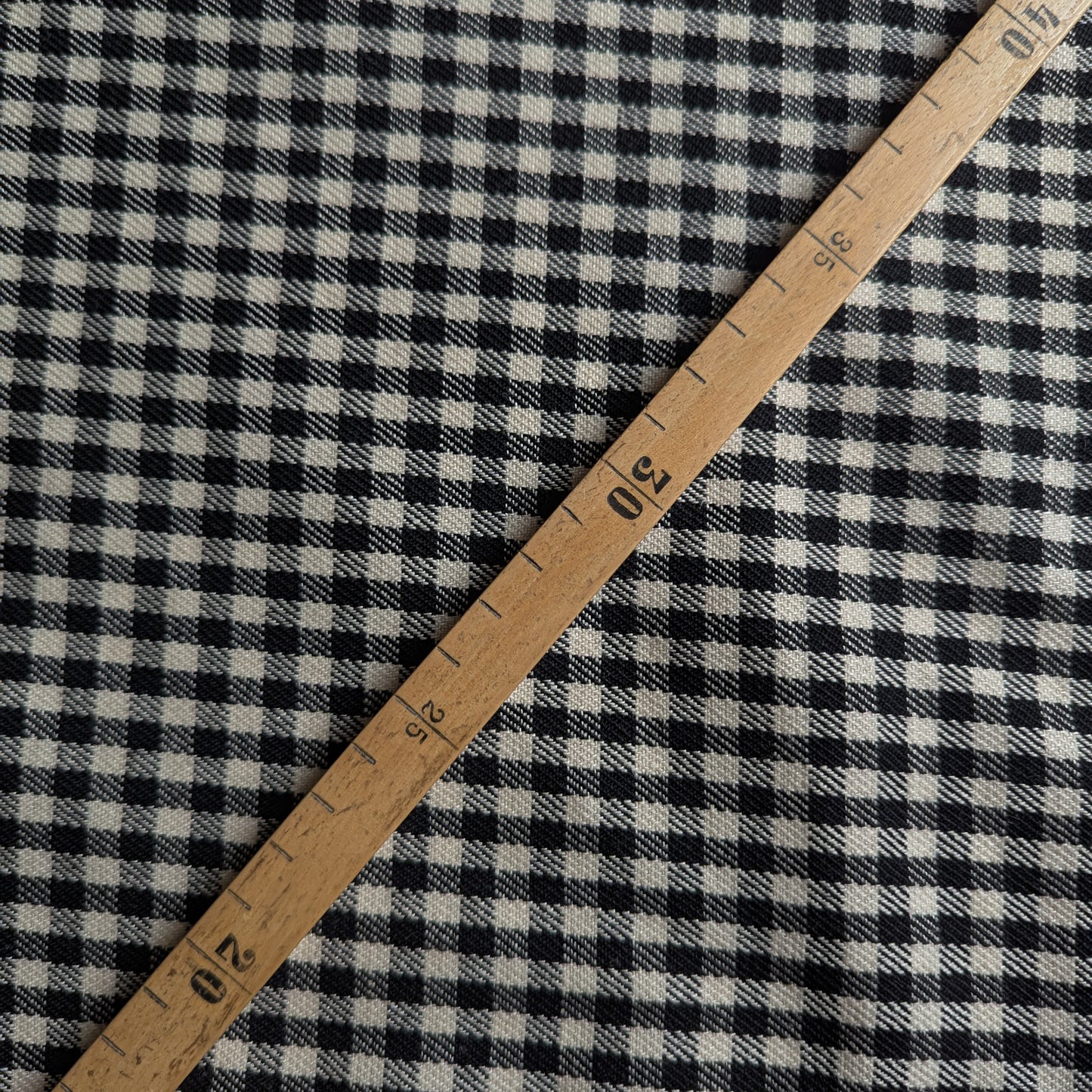 Black and white gingham wool fabric with a wooden ruler showing measurements.