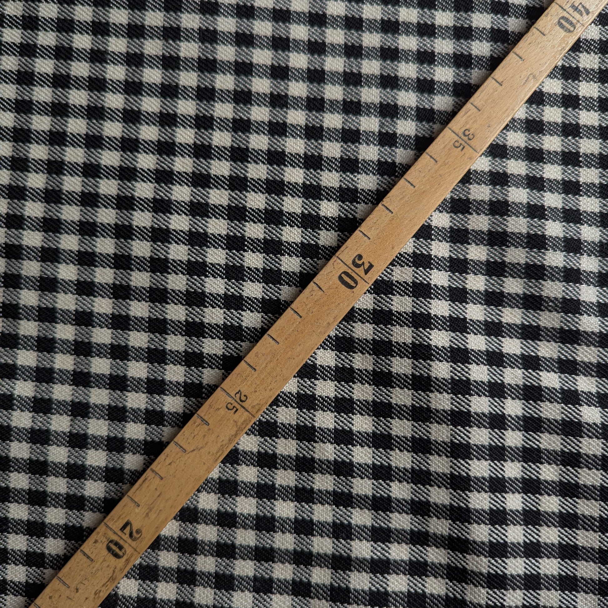 Black and white gingham wool fabric with a wooden ruler showing measurements.