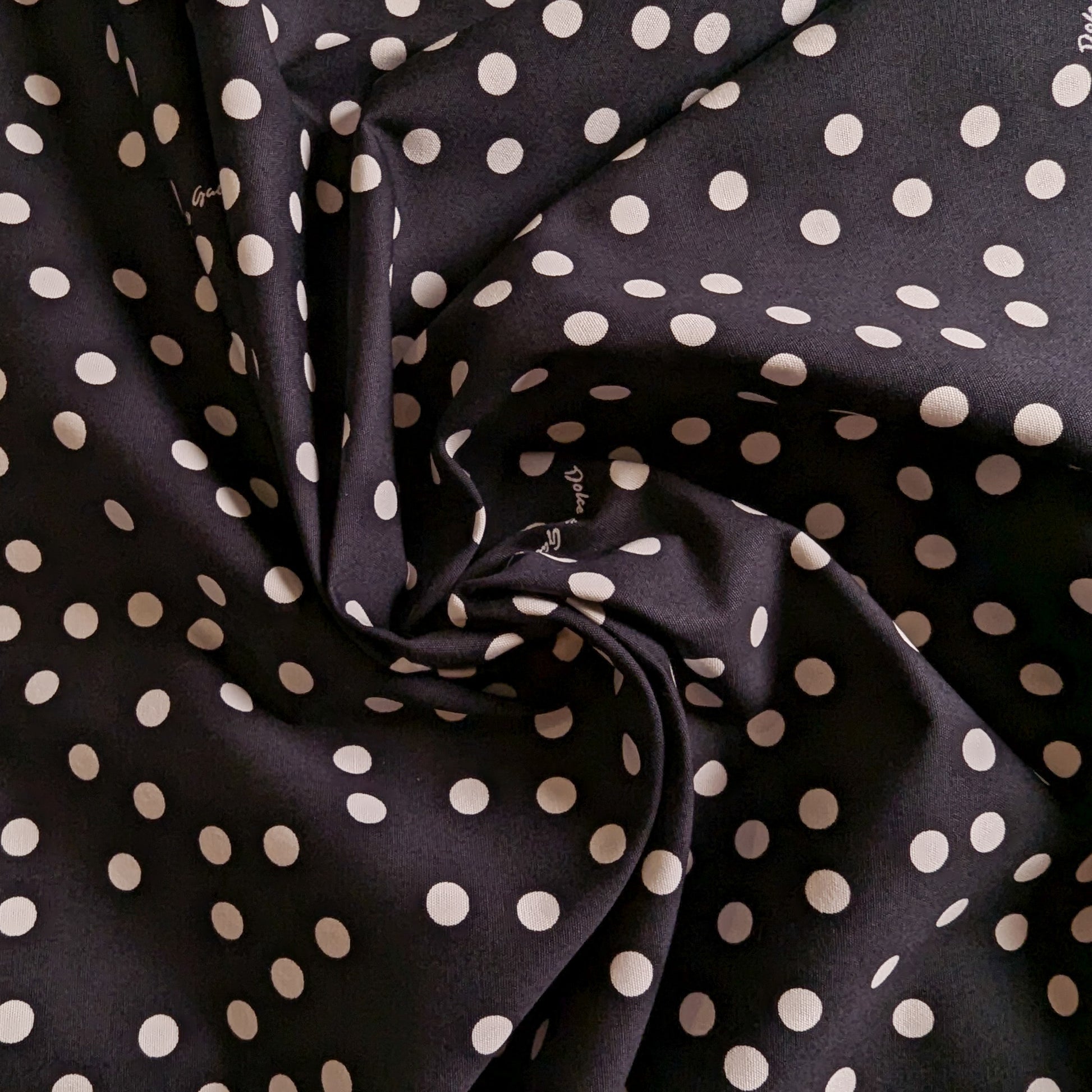 Black D&G deadstock cotton fabric with white polka dots, folded to show texture.