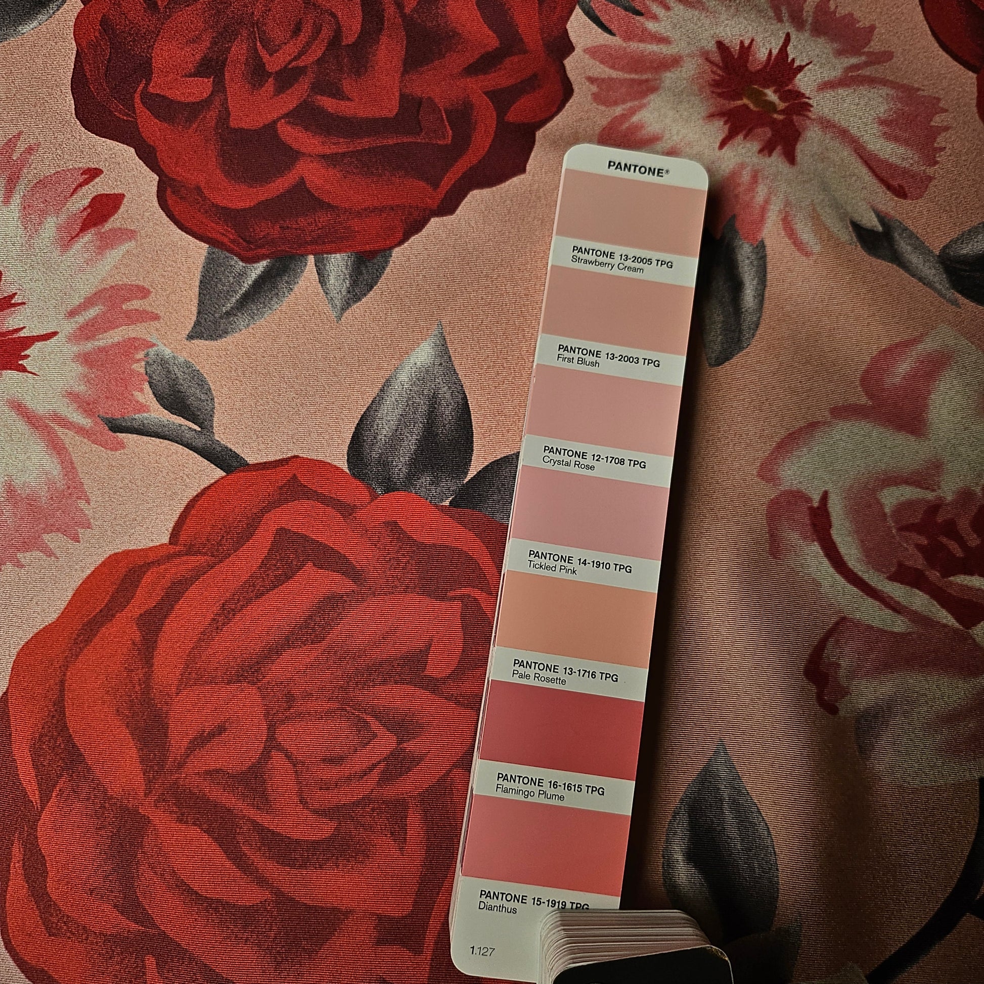 Deadstock Ferragamo silk twill fabric with large red and pink floral print, next to a Pantone color swatch.