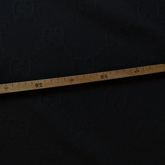 Black G*cci polyester jacquard fabric, textured with a woven tone-on-tone logo, measured by a wooden tape.