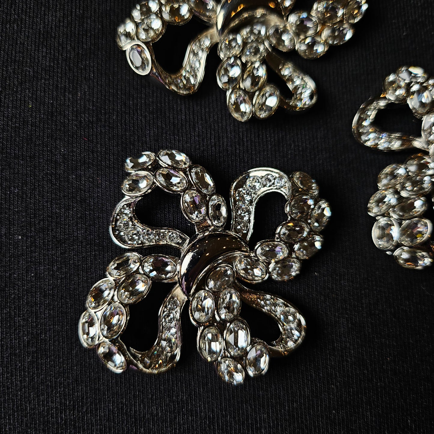 D&G silver-plated metal ornament with sparkling Swarovski stones, filigree bow design, approx. 4x4 cm.