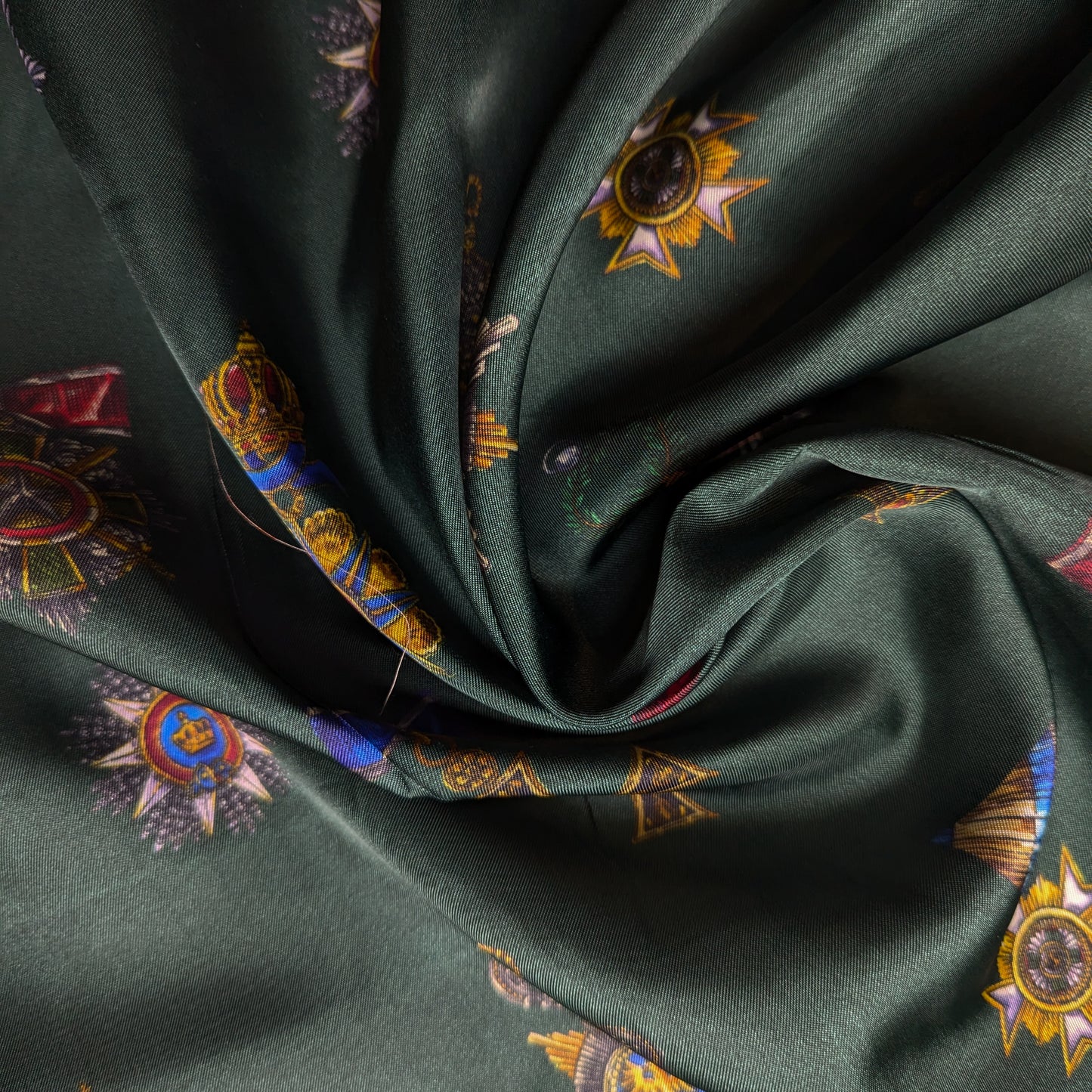 D&G deadstock viscose twill fabric in British Green with a colorful military order pattern.