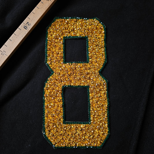 Gold sequin and stone "8" patch with green border, 10x19cm, on black fabric.