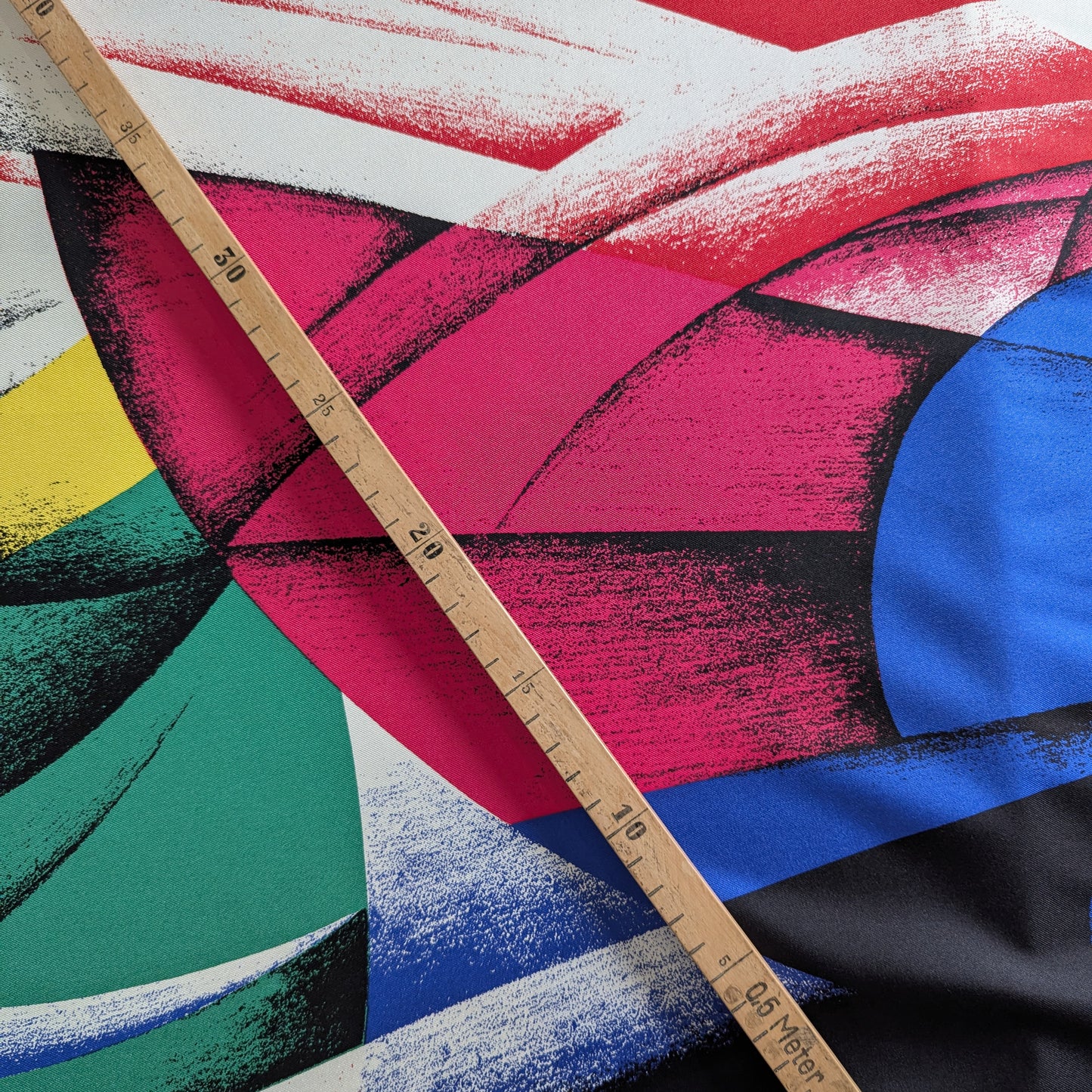 Versace deadstock silk fabric with a vibrant, multicolor XXL abstract print and a wooden ruler.