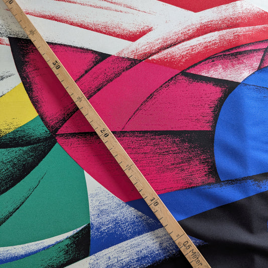 Versace deadstock silk fabric with a vibrant, multicolor XXL abstract print and a wooden ruler.