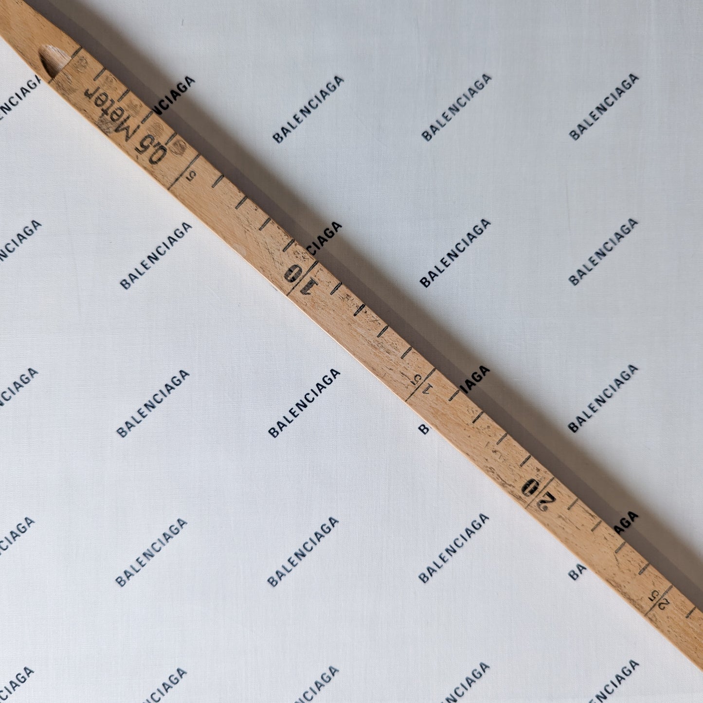 White Balenciaga cotton poplin deadstock fabric with logo print, measured by a wooden ruler.