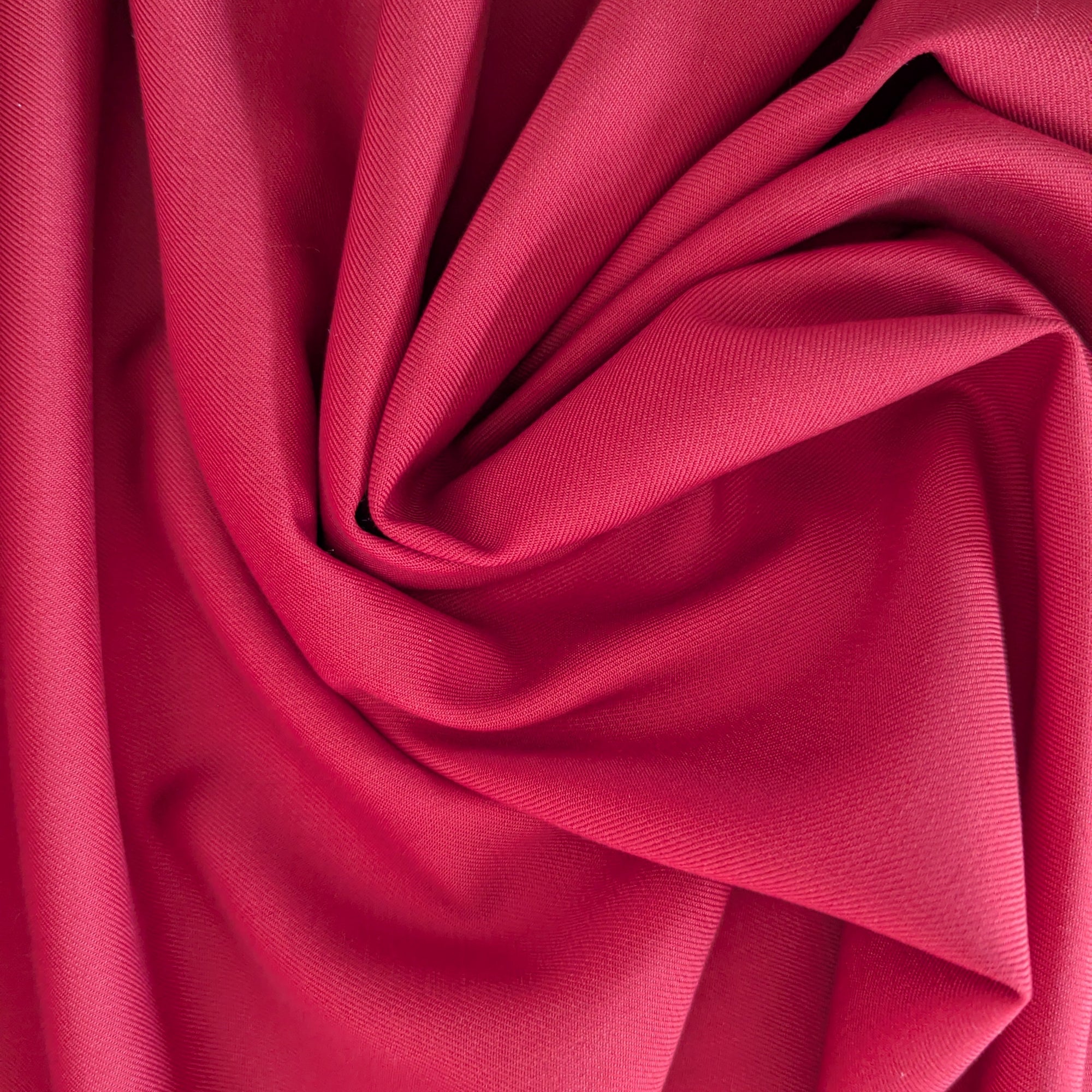 Deep red deadstock wool fabric, soft with light stretch, elegantly draped in folds.