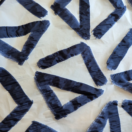 Deadstock D*or polyester panel: dark blue geometric V-shapes appliquéd on white, ideal for jackets/vests.