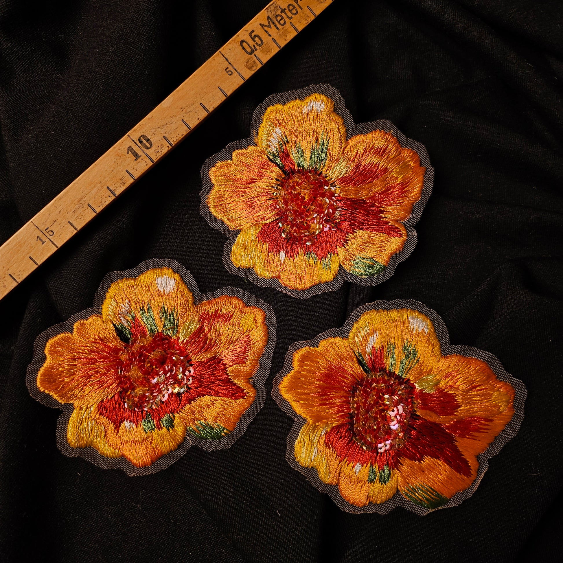 Three hand-embroidered D&G flower patches, 7x9cm, with orange, yellow, and red petals on black fabric.