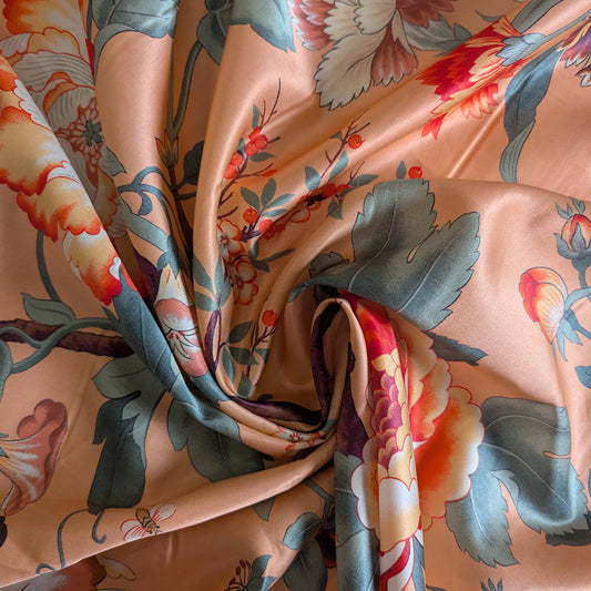 Apricot deadstock viscose satin fabric with a vibrant floral and berry pattern.
