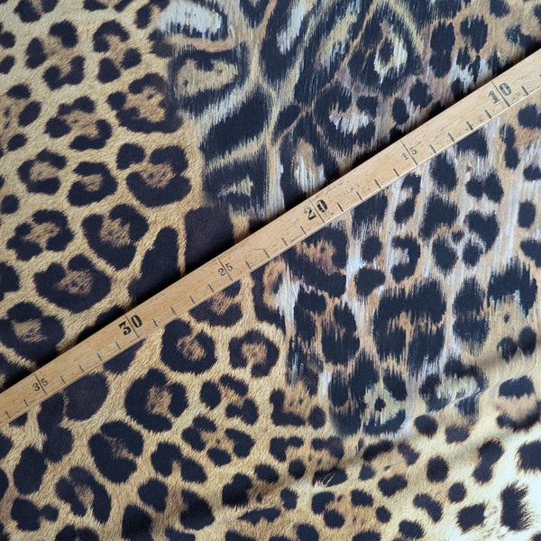 Elastic brown and black leopard print Lycra fabric with a wooden ruler showing measurements.