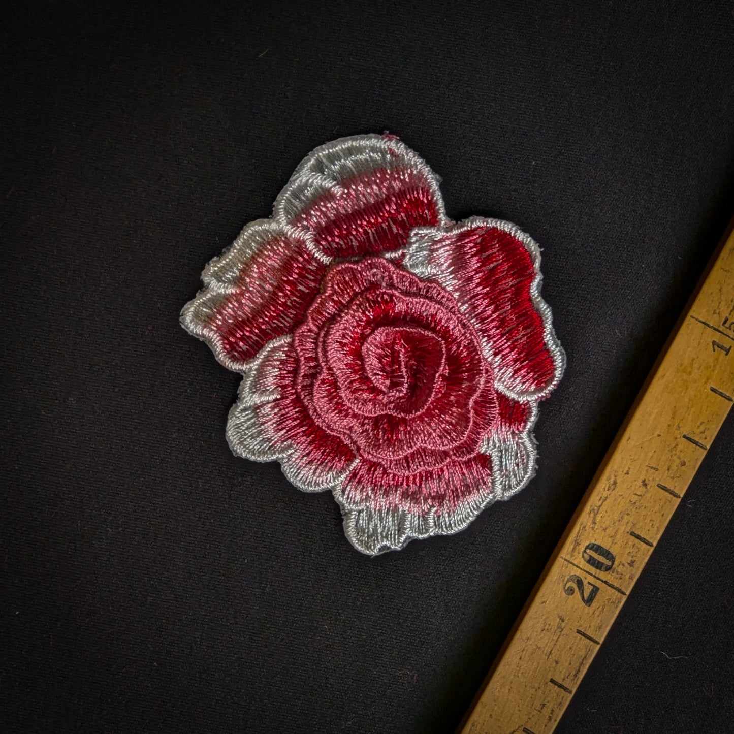D&G red 3D rose embroidery patch with silver outline, 7.5x6.5 cm, on dark fabric with ruler.