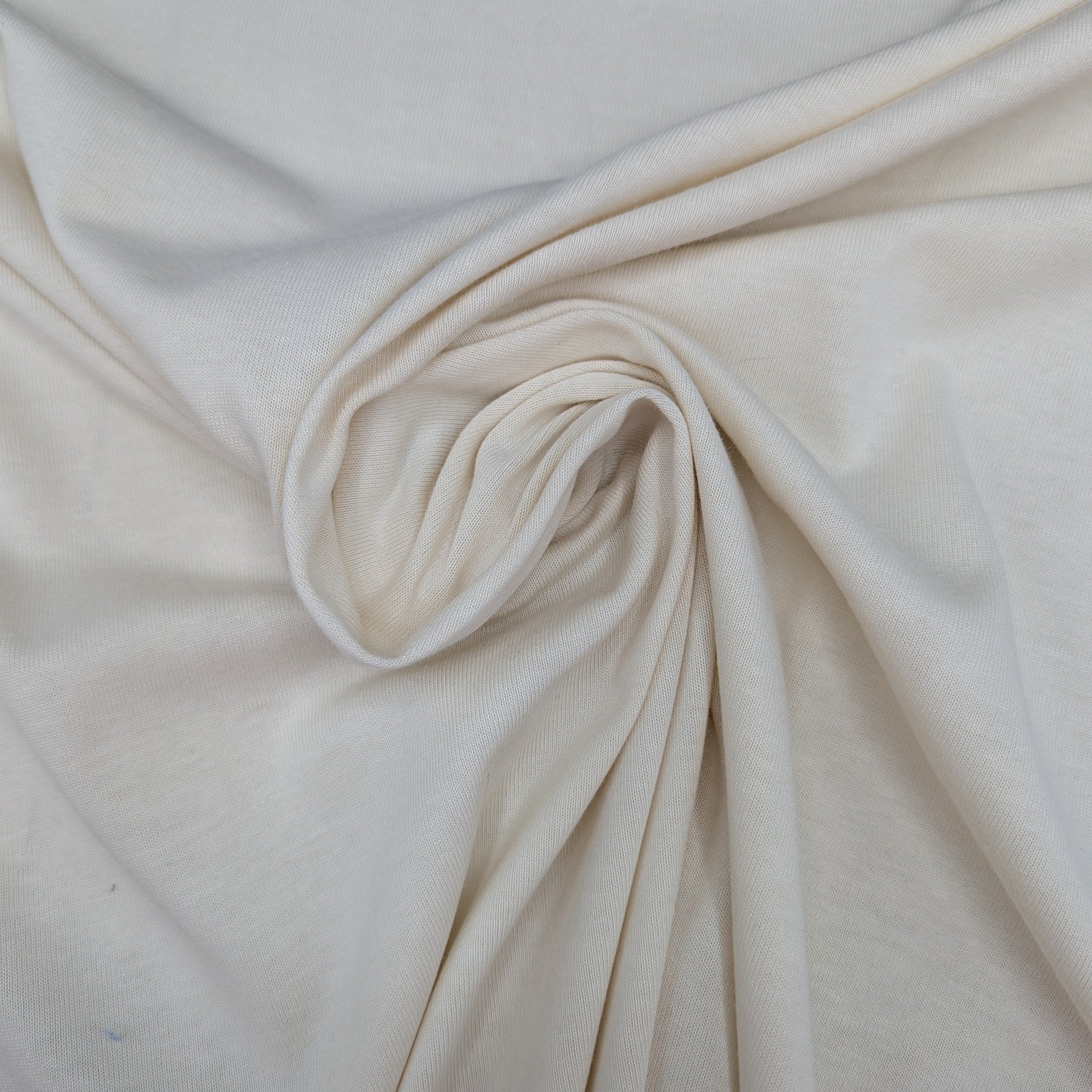 Soft natural white D*or deadstock cotton jersey fabric, 155cm wide, draped with gentle folds.