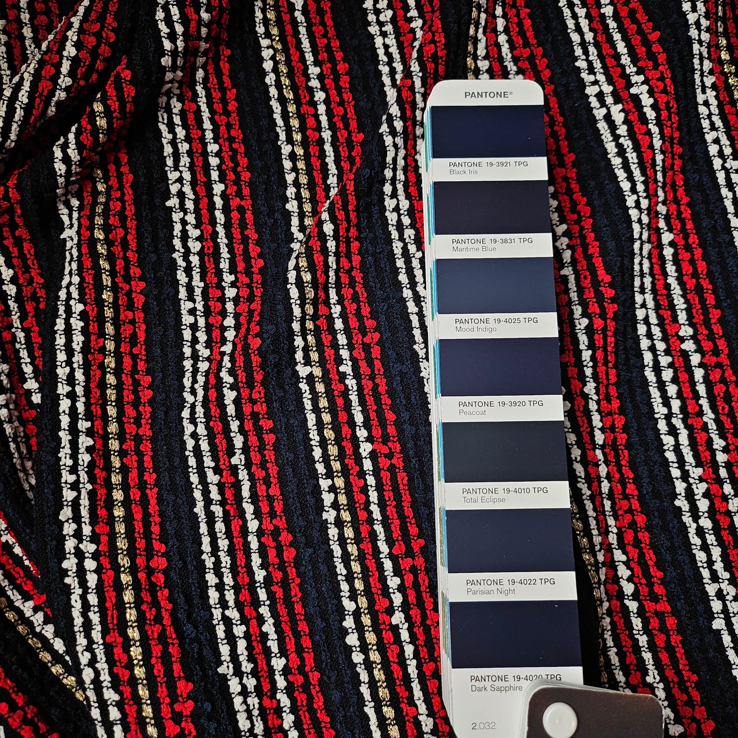Dark blue tweed fabric with red, white, and gold stripes, shown with a Pantone color swatch.
