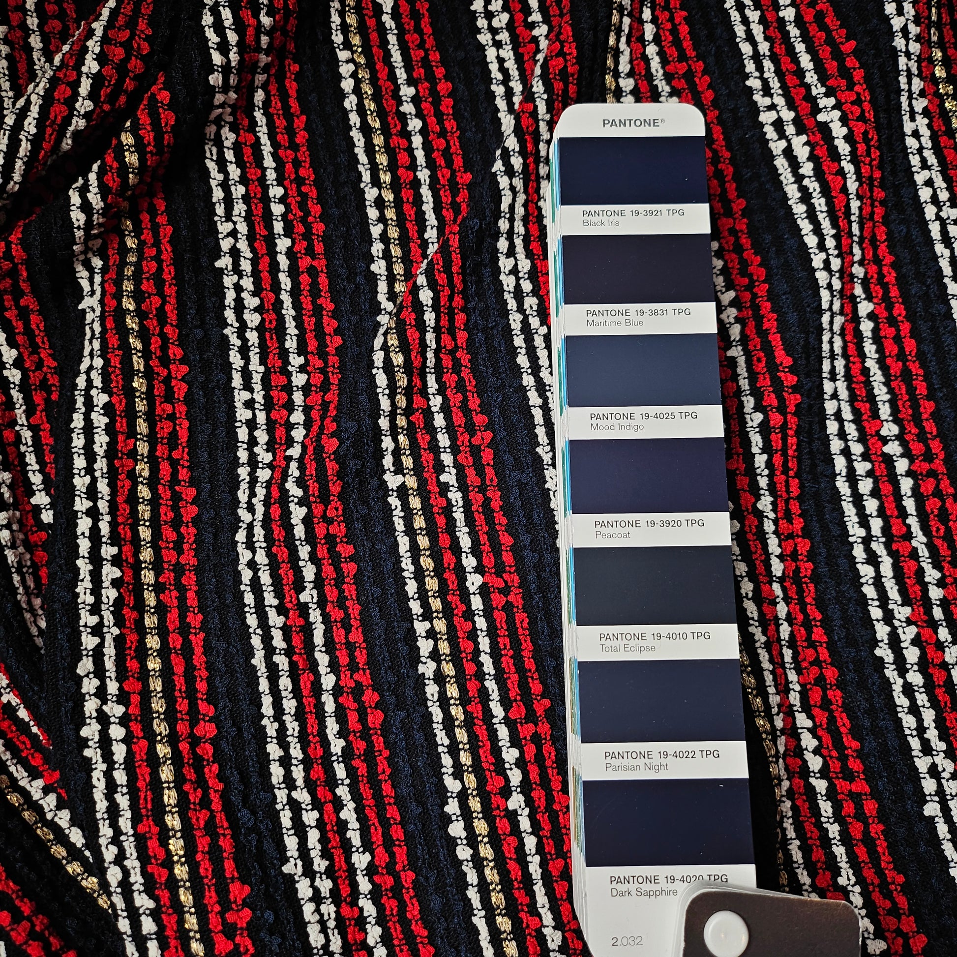 Dark blue tweed fabric with red, white, and gold stripes, shown with a Pantone color swatch.