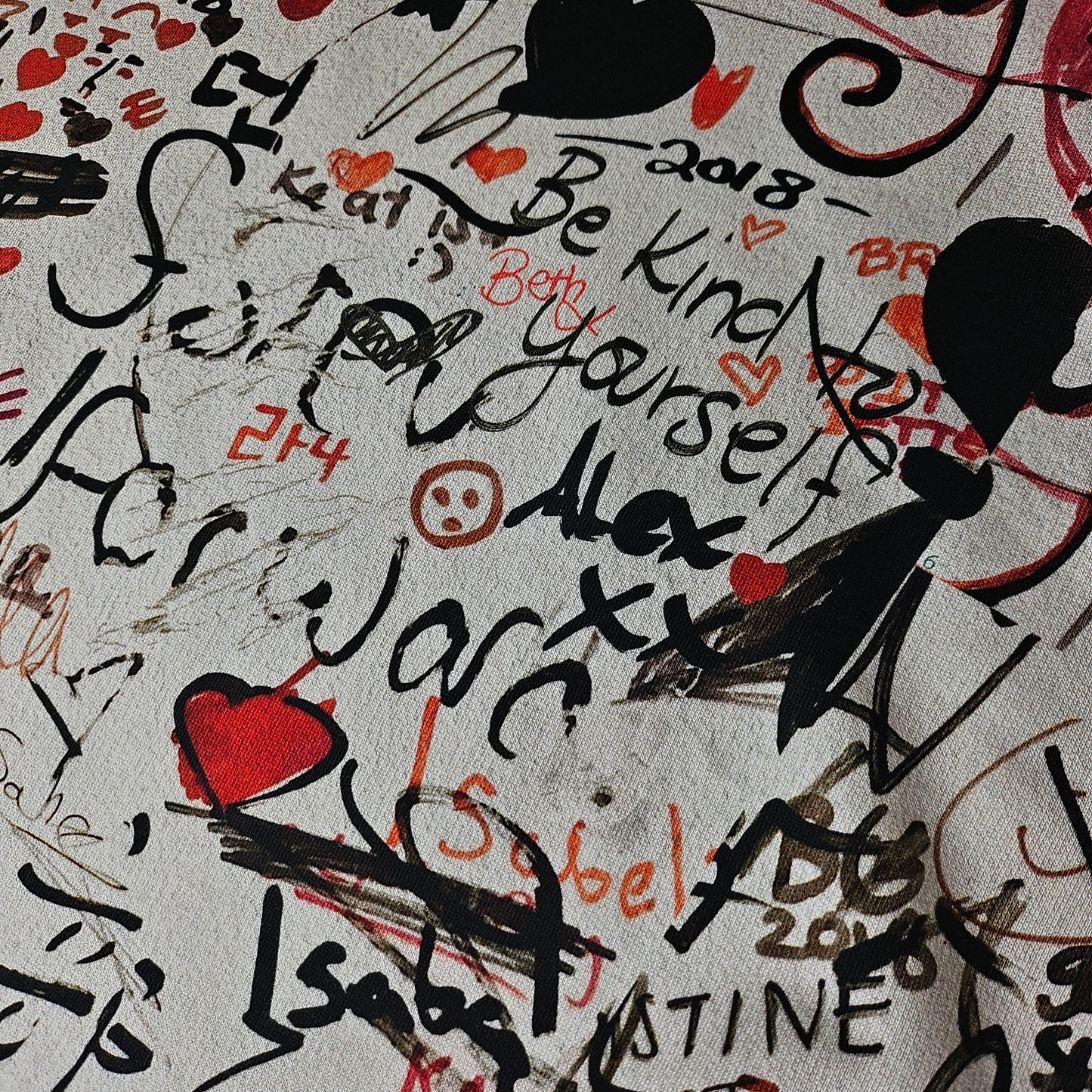 White deadstock Burberry sweat panel fabric with black, red, and orange graffiti-style text and hearts.