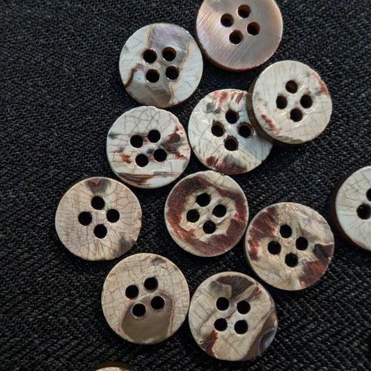 Set of 15 natural mother-of-pearl buttons, 1cm, with unique brown and white patterns and four holes.