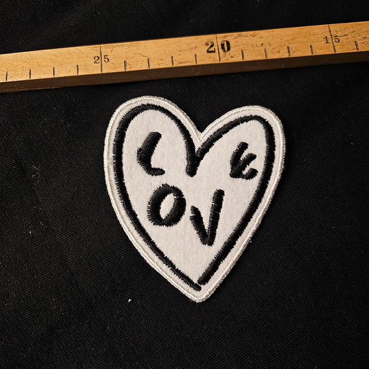 White felt heart patch with "LOVE" embroidered in black, 8x8 cm.