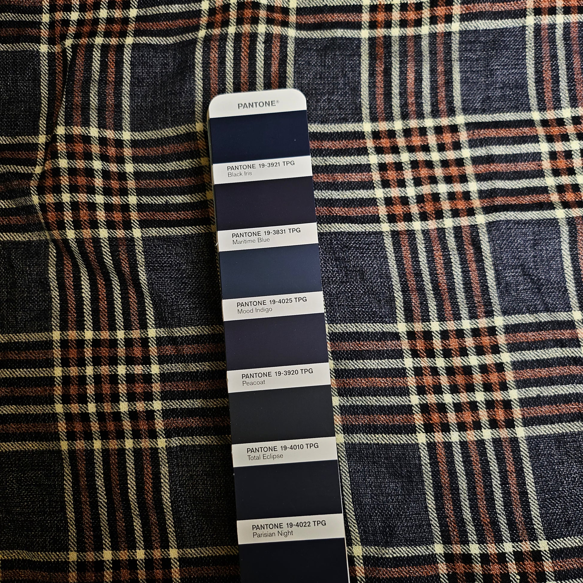 Dark blue, brown, and cream plaid linen-silk fabric with a Pantone color swatch displaying various dark blue shades.